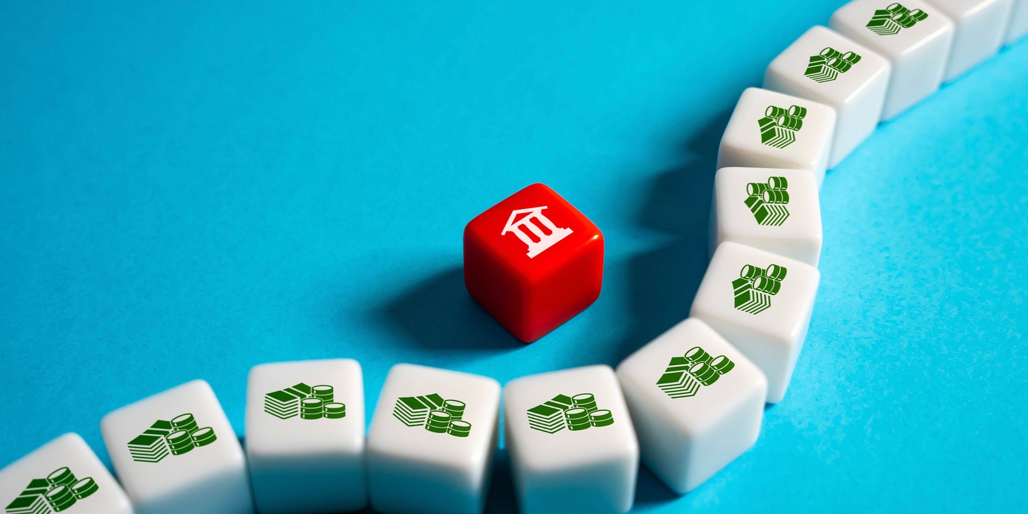 A red cube featuring a white bank icon stands out among a curved arrangement of white cubes with green money stack icons. The scene is set against a vibrant blue background, emphasizing the contrast between the red and white cubes. The composition suggests themes of finance, banking, and monetary systems.