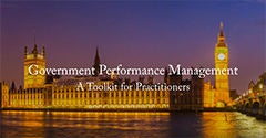 Nighttime view of a historic riverside government building illuminated with warm golden lights. The scene features a prominent clock tower and its reflection shimmering on the water. Overlaid text reads "Government Performance Management" and "A Toolkit for Practitioners." The overall composition suggests a professional resource focused on public sector performance.