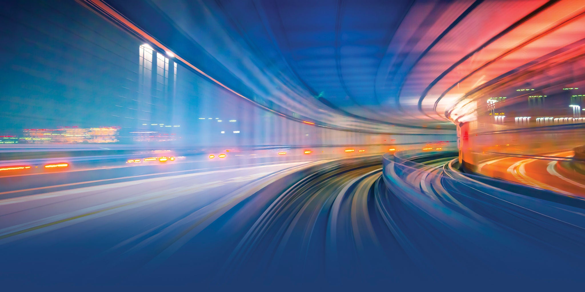 Motion-blurred view of curved transit tracks in a tunnel, with blue and orange light streaks.