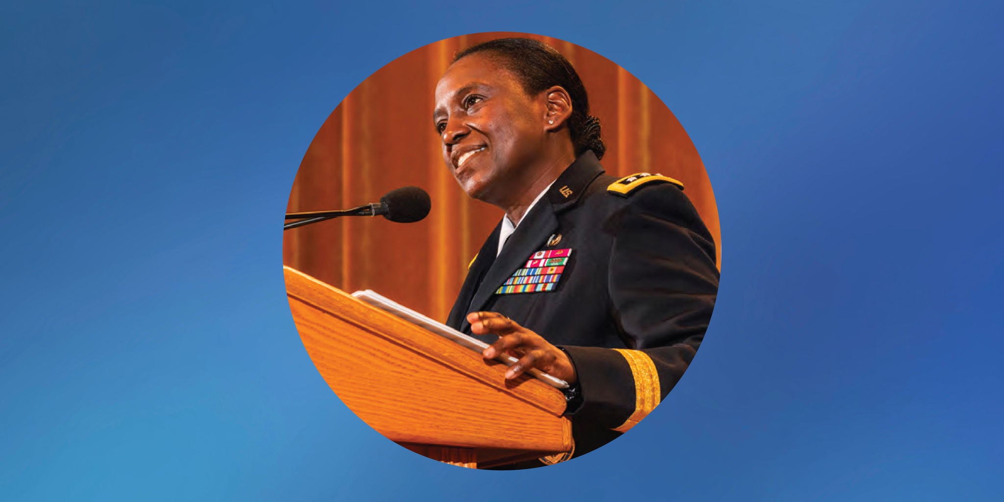 Uniformed speaker stands at a wooden podium with a microphone