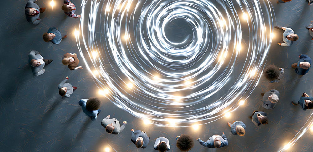 Overhead view of people surrounding glowing concentric spiral light trails on a dark floor.
